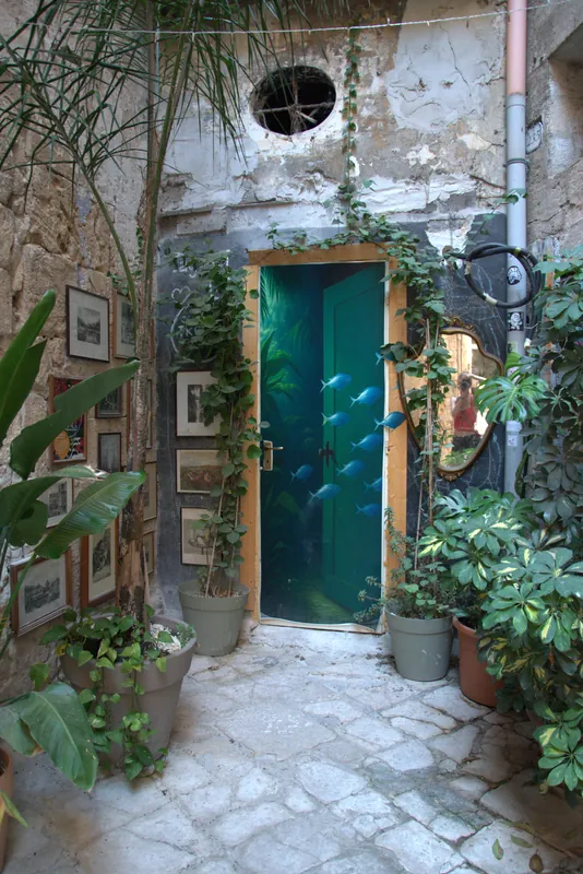 Une porte verte parmi les plantes d'une cour, Tarente
